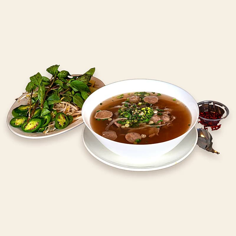 Beef phở with meatballs and the plate of herbs, bean sprouts and jalapeños that comes with it