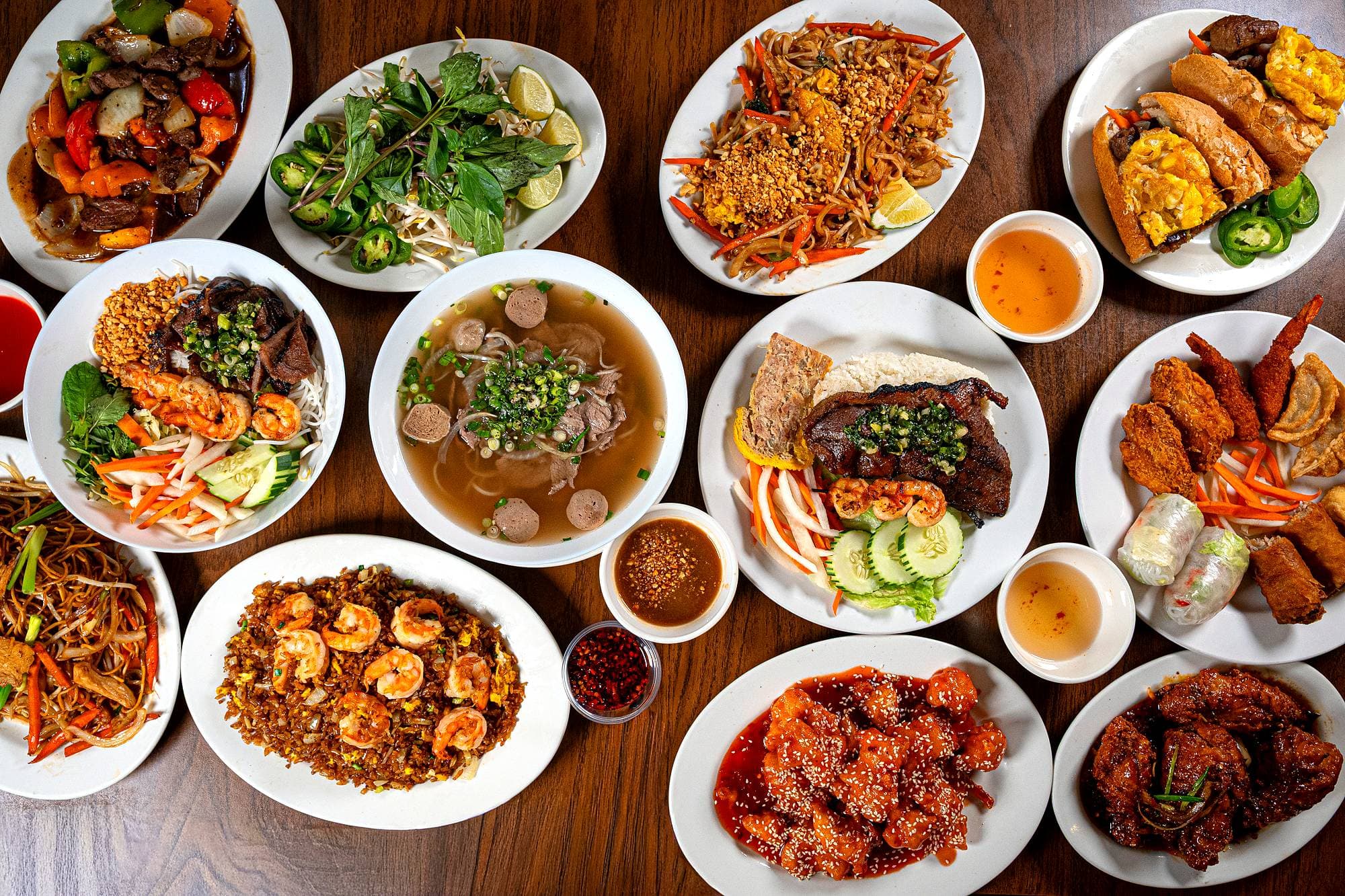 A table at Saigon Palace set with phở, vermicelli salad, shrimp fried rice, lo mein, egg rolls and sesame chicken