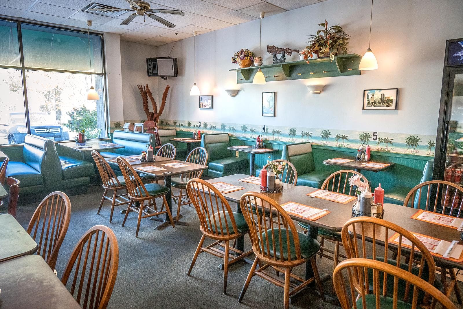 Rows of green booths and tables under the palm-tree wallpaper border