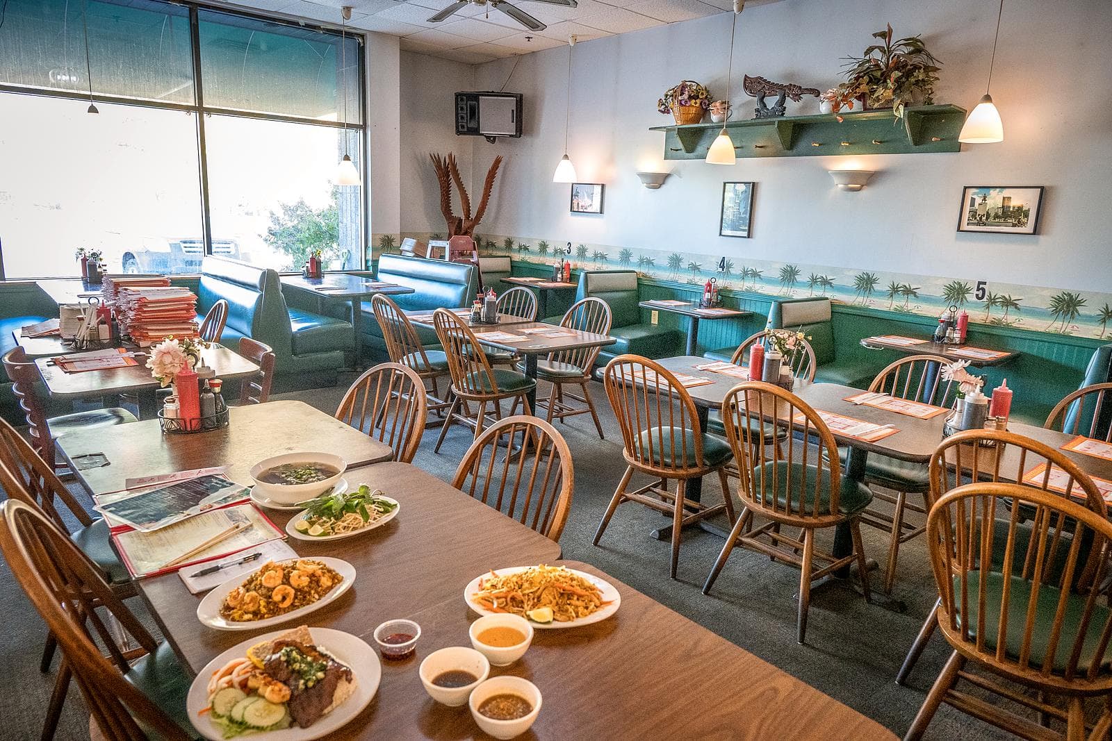 The Saigon Palace dining room, with wooden chairs, green booths and plants on the shelves